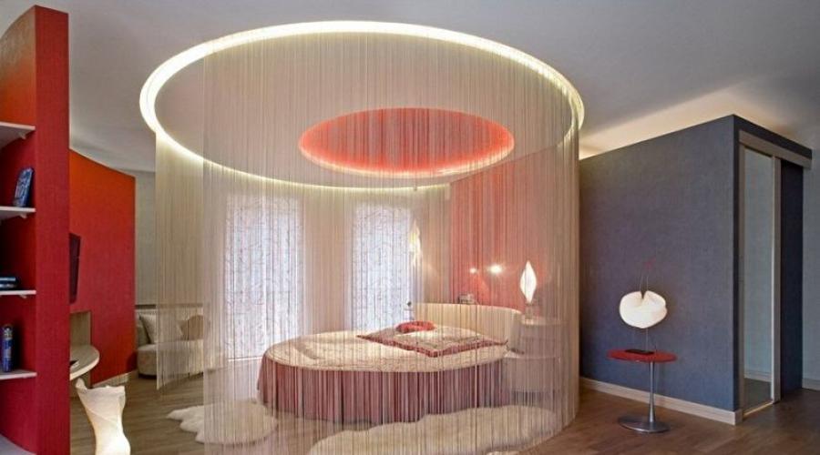Innenraum eines weißen Zimmers mit einem runden Bett.  Runde Betten – eine mutige Lösung für die Inneneinrichtung eines modernen Schlafzimmers